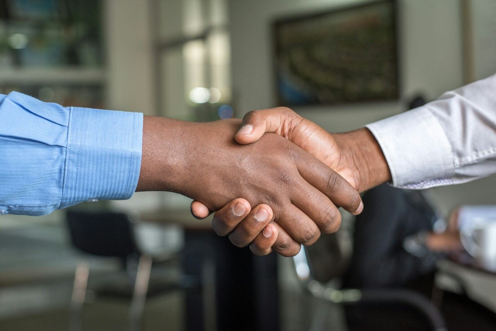 Two business people shaking hands across a desk