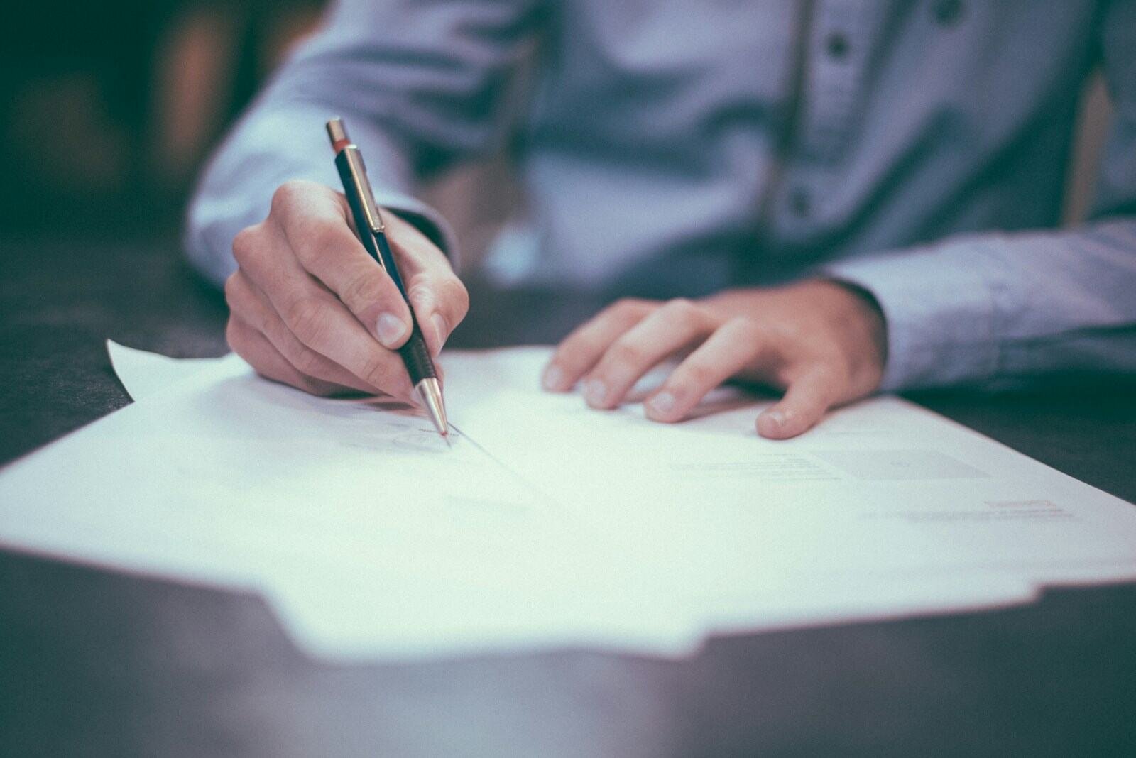 Hand signing a document with a pen